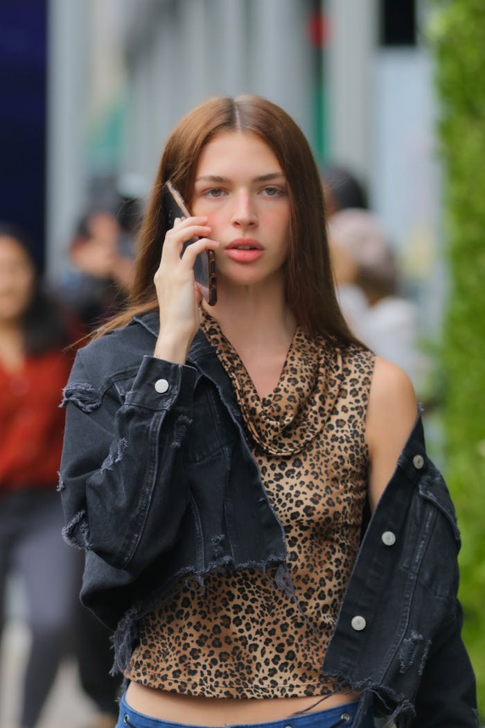 Stylish young woman on cellphone in New York City street, wearing leopard print and denim.